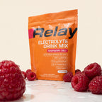 variant:49281673298157 Orange Relay Electrolyte Drink Mix package with raspberries on a light background