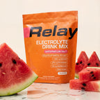 variant:49281673265389 Orange Relay Electrolyte Drink Mix package with watermelon slices on a light background